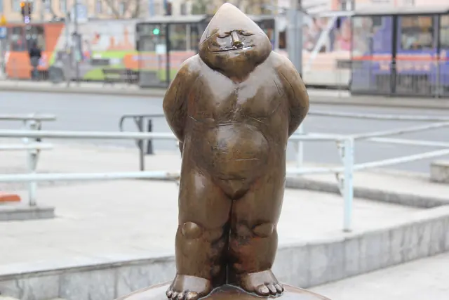 Papa Krasnal, the first bronze dwarf in Wrocław, standing on Świdnicka Street with a tram behind it