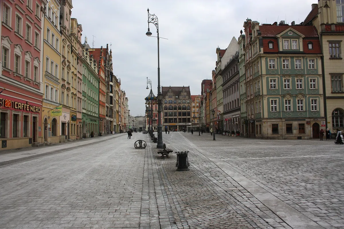 A wide cobbled street of the Market Square in Wrocław lined with colourful tenement houses